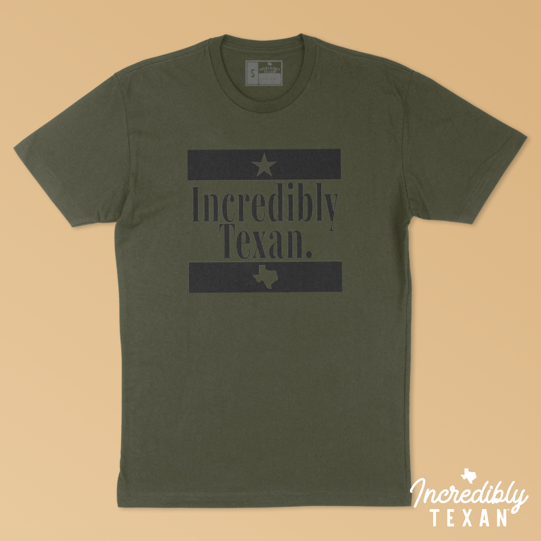 An olive green short sleeve shirt with the words "Incredibly Texan" printed in black, with a black bar and star above and a black bar and Texas shape below.