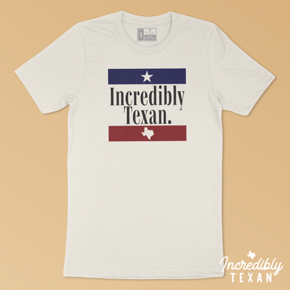An off-white short sleeve shirt with the words "Incredibly Texan" printed in black, with a blue bar and star above and a red bar and Texas shape below.