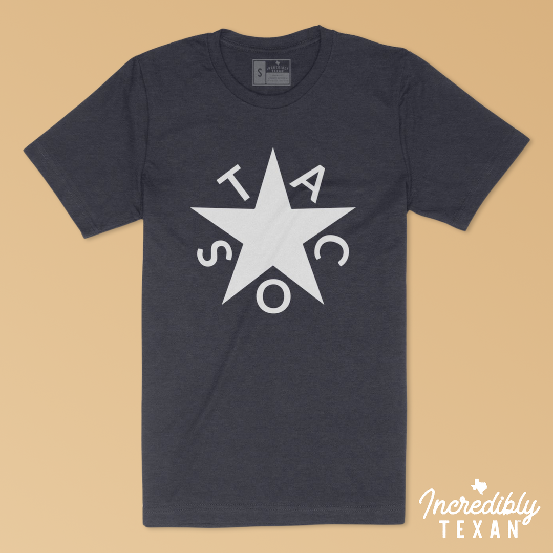 A dark navy blue short sleeve t-shirt with the Zavala star of Texas printed in white, with the word "TACOS" surrounding the star.